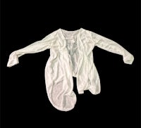 a white cardigan hanging on a black background