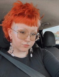 a woman in a car with orange hair and glasses