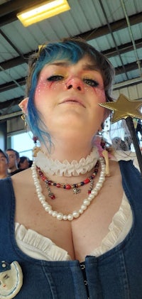 a woman with blue hair and pearls is holding a wand